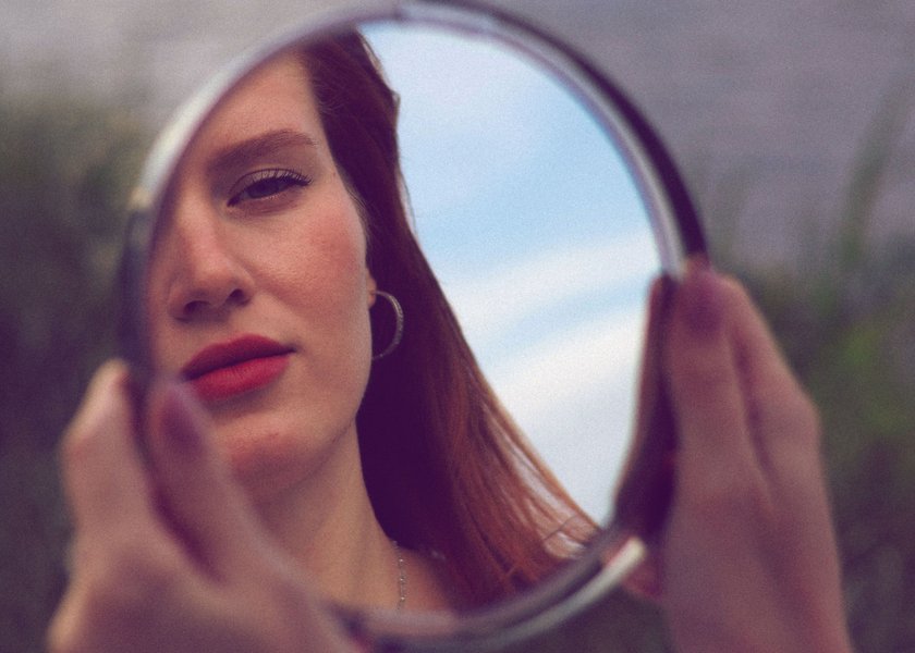 Frau, die sich in Spiegel betrachtet