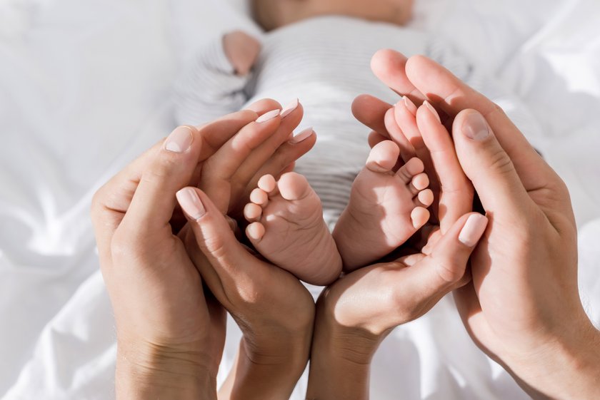 Mama und Papa halten die Füße ihres Babys in den Händen