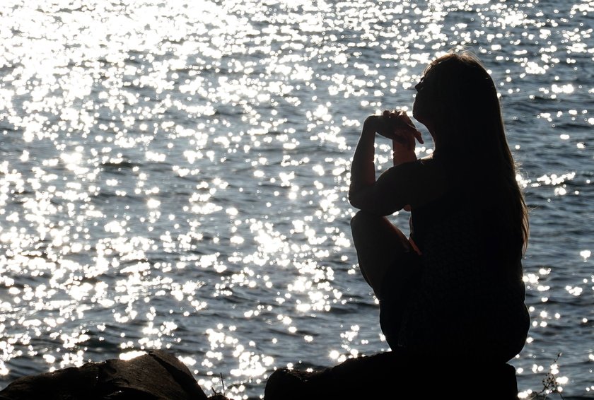 Frau sitzt allein am wasser