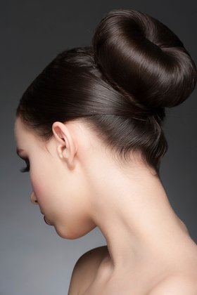 Portrait of young beautiful woman with creative elegant hairstyle, hair bun. Rear view Portrait of young beautiful woman with creative elegant hairstyle, hair bun. Rear view