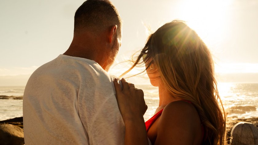 Ein Pärchen ist am Strand und blickt gemeinsam aufs Meer im Sonnenaufgang