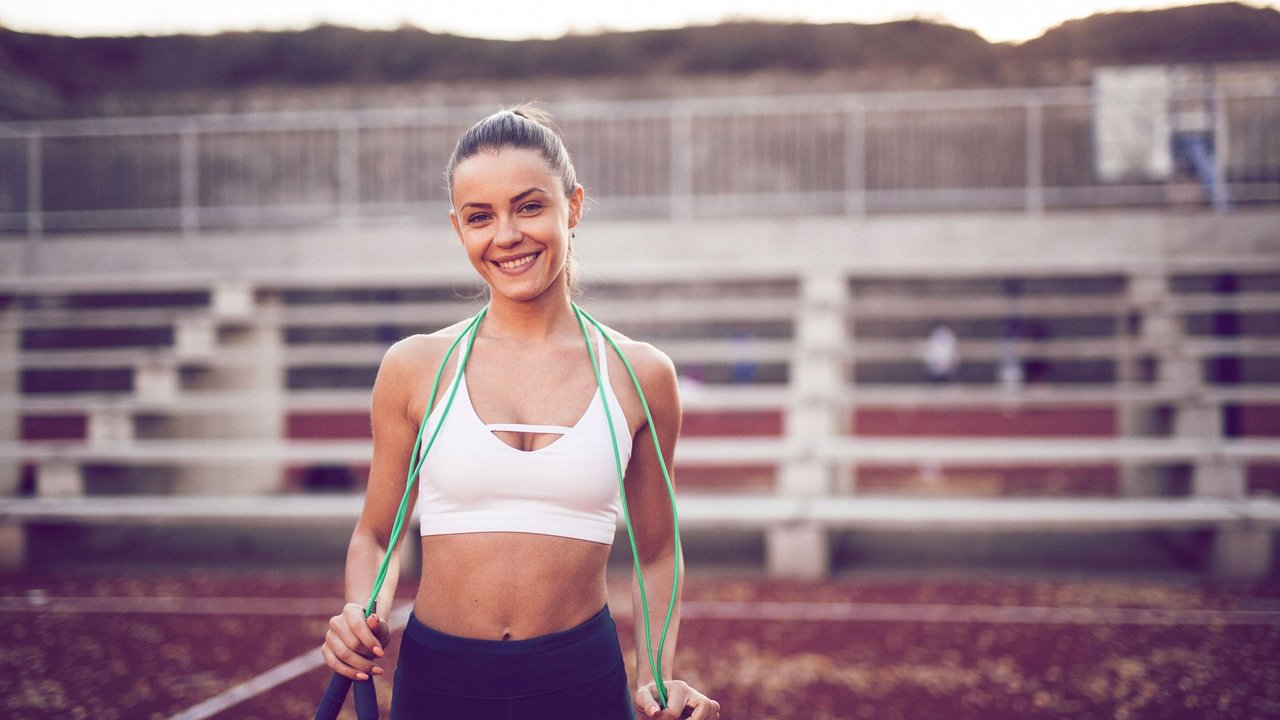 frau auf Sportplatz mit Springseil
