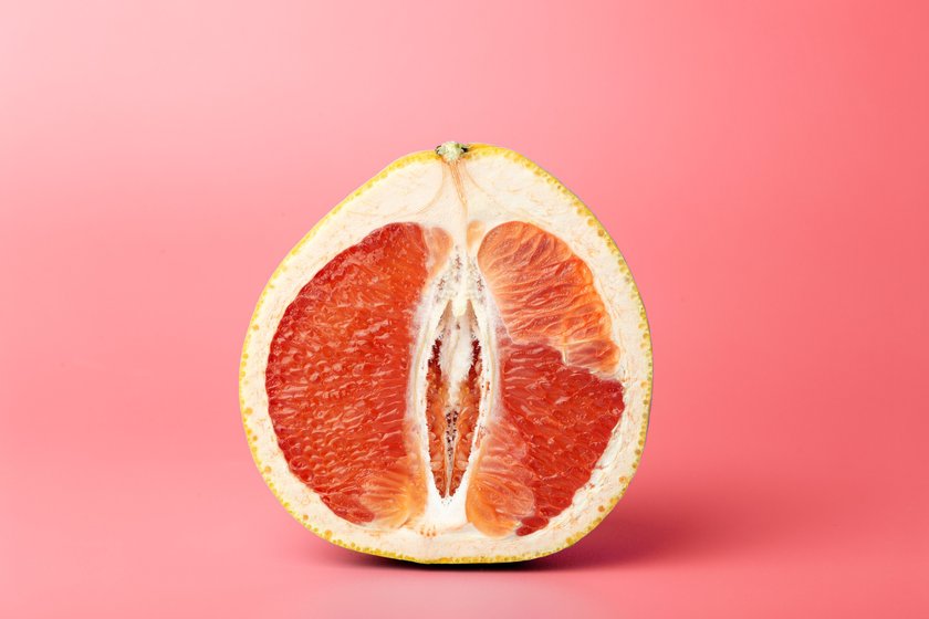 Grapefruit minimal erotic concept. Half a juicy grapefruit close up on a colored background.