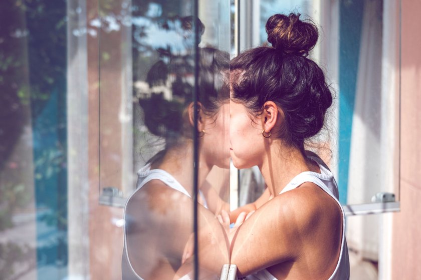 Frau steht am Fenster, Reflektion in der Scheibe