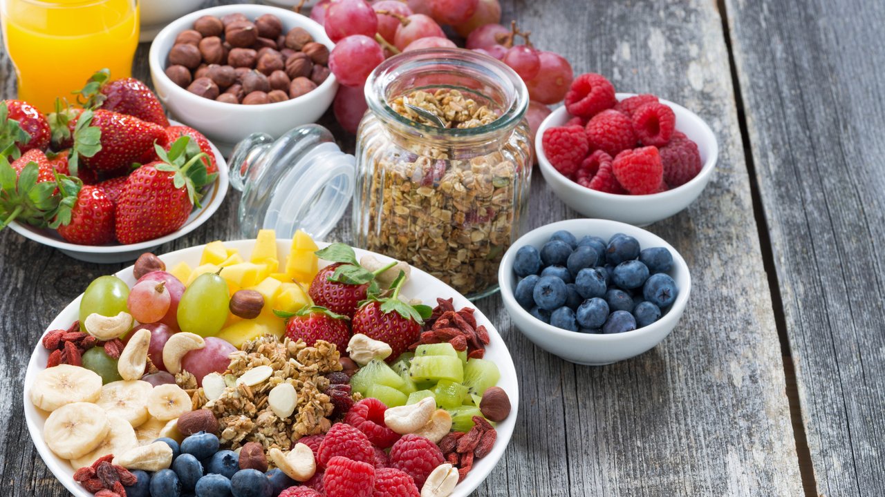 ingredients for a healthy breakfast - berries, fruit, muesli and wooden background, top view, horizontal