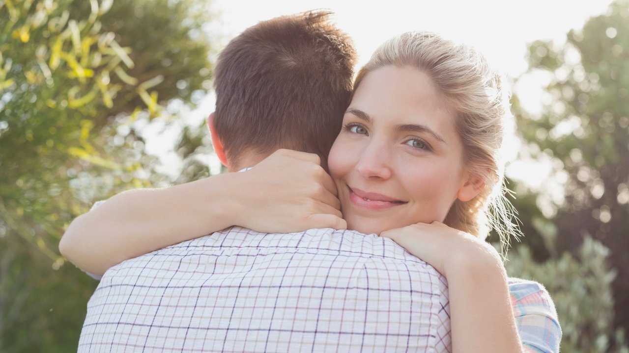 Close-up of a smiling young couple embracing in the park
