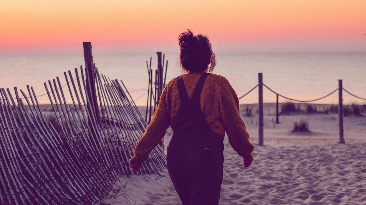 Frau, die bei Sonnenaufgang aufs Meer zuläuft