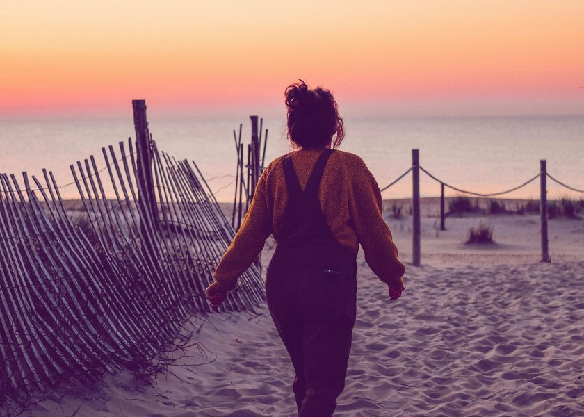 Frau, die bei Sonnenaufgang aufs Meer zuläuft
