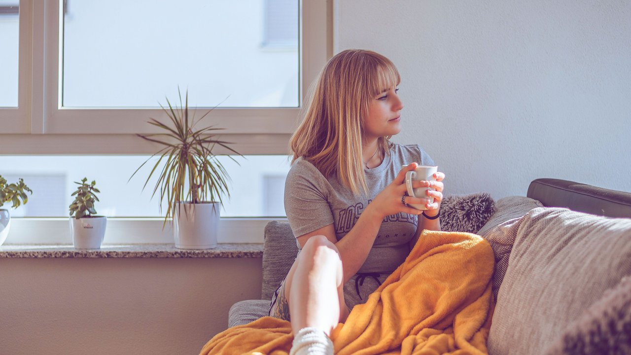Frau, die mit einem Kaffee auf der Couch sitzt