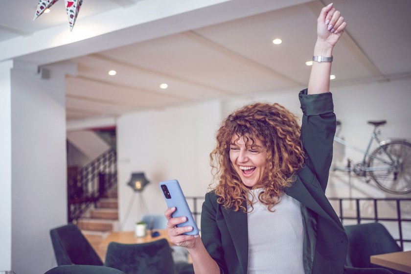 Frau schau aufs Handy und freut sich