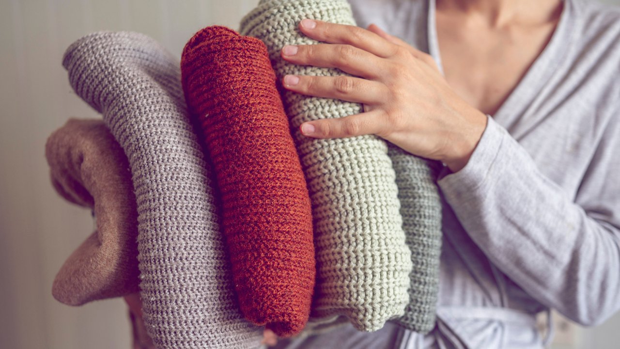 Woman holding clean folded sweaters at home model released, Symbolfoto property released, ANAF00232