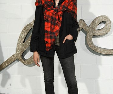 Model Agyness Dean trägt eine Röhrenjeans, Turnschuhe und eine weite Jacke mit Halstuch im Boyfriend-Look