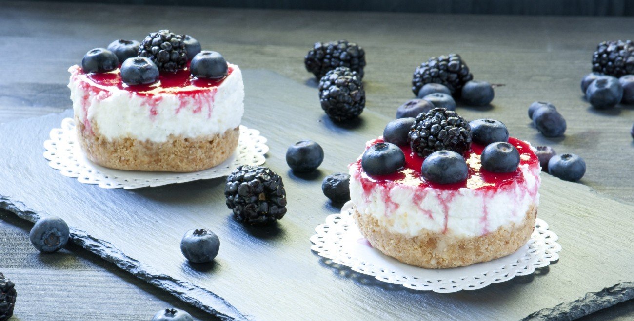 Kleine Cheesecake mit Heidelbeeren auf einer Schieferplatte Kleine Cheesecake mit Heidelbeeren auf einer Schieferplatte