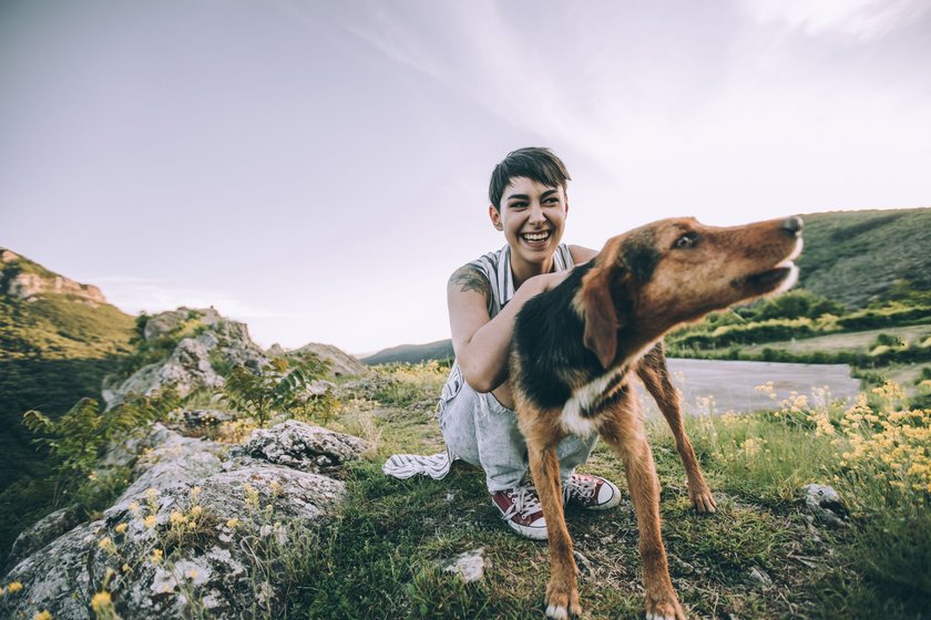 Eine Frau und ihr Hund sind in den Bergen unterwegs und sehen glücklich aus
