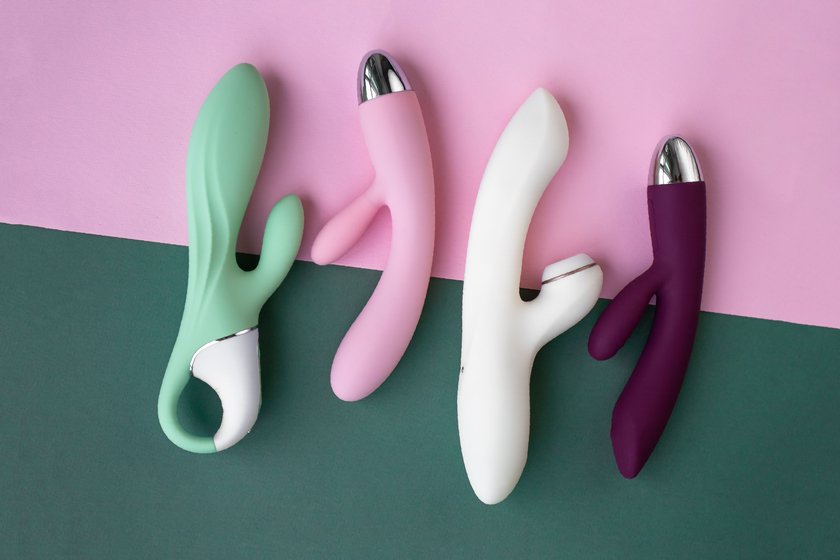 Collection of different types of sex toys on a green and pink background. Sex toys for adults, dildos, vibrators, clitoral stimulators.