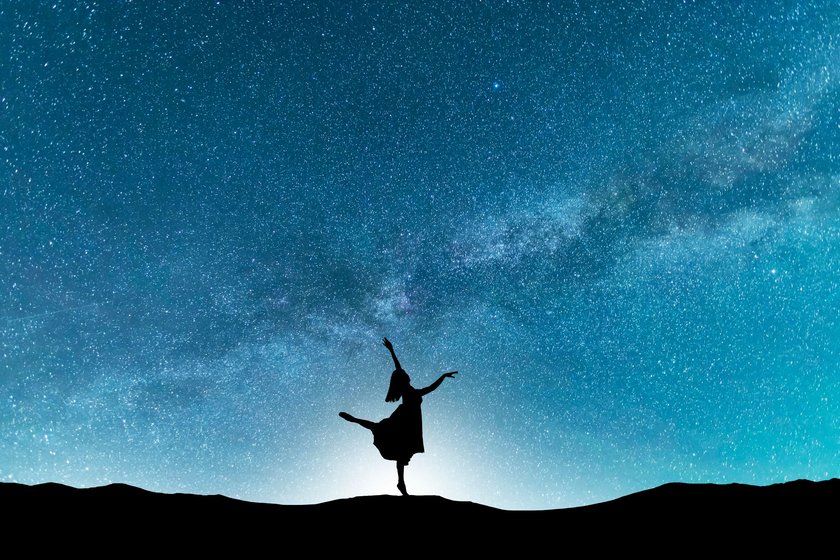 Woman silhouette dancing in the night, on the bright Milky Way Galaxy background.