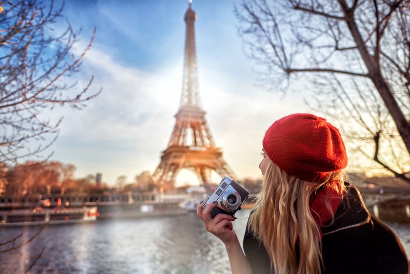 Frau mit roter Baret Mütze und Kamera vor dem Eifelturm