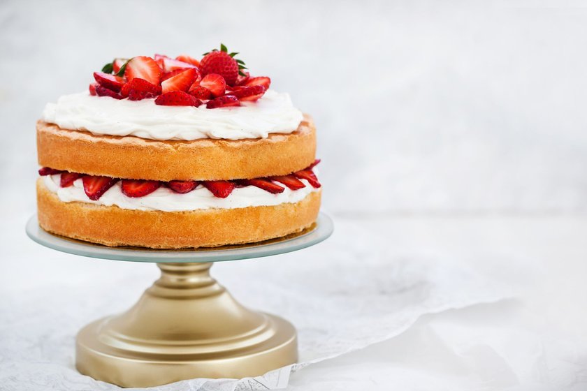 Victoria`s sponge cake, delicious homemade vanilla cake decorated with whipped cream and fresh strawberries, on white