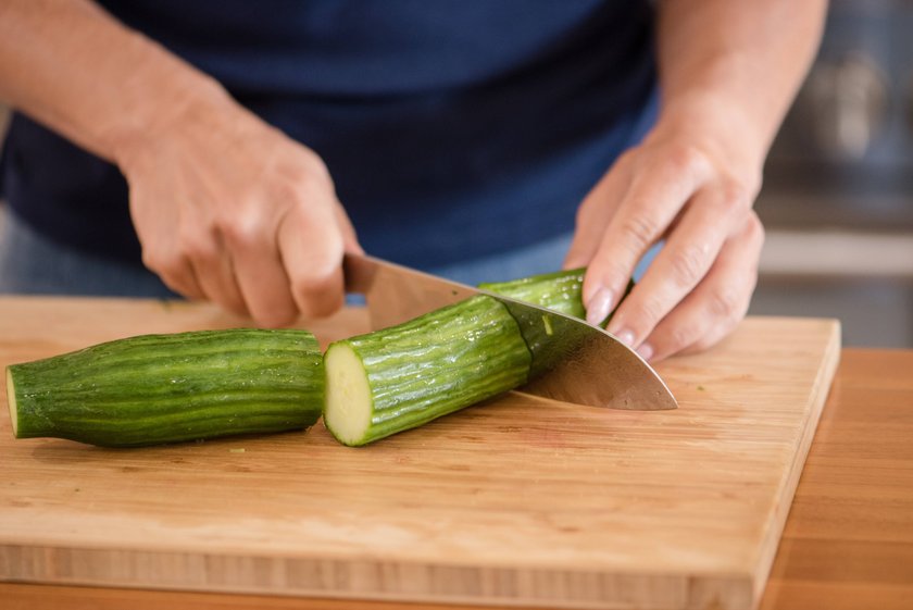 Eine Frau schneidet eine Gurke.