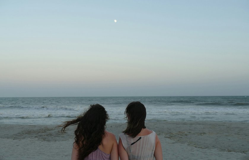 zwei Frauen, die am Strand aufs Wasser schauen