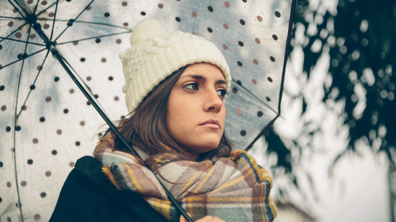 Closeup of young beautiful girl under a umbrella in an autumn rainy day