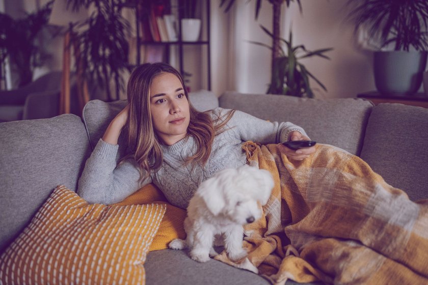 Frau auf Couch schaut TV
