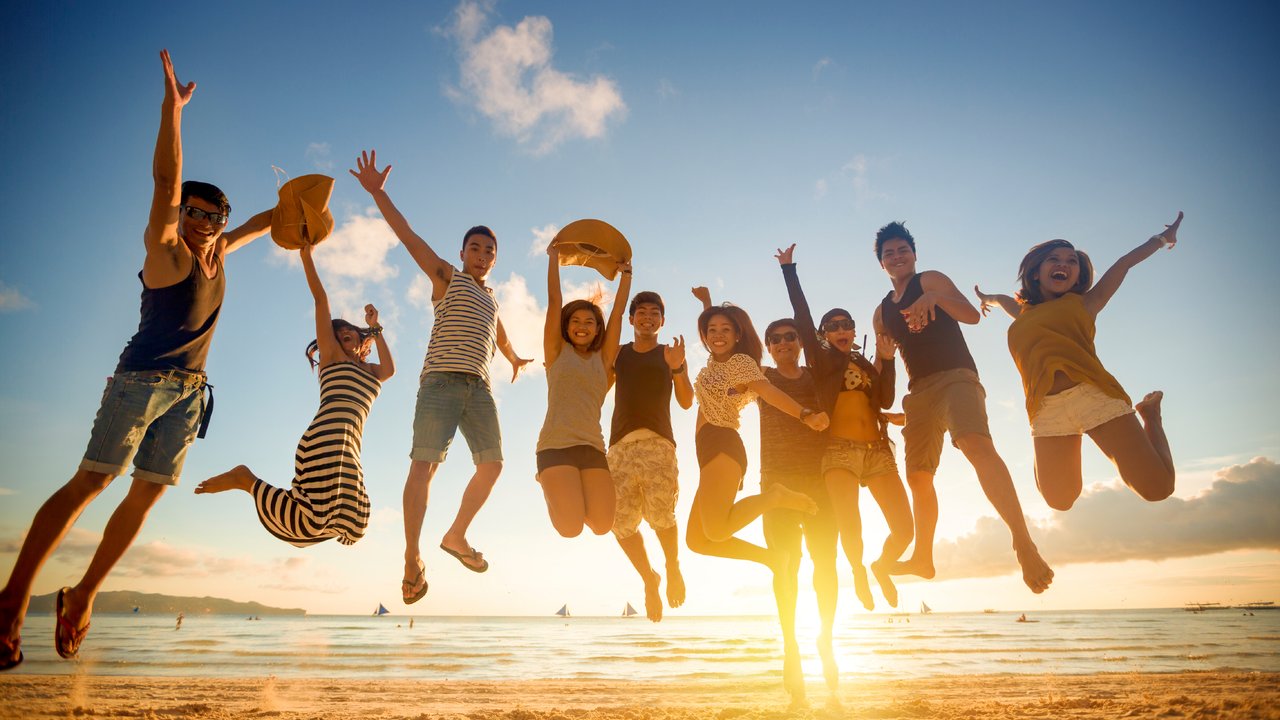 Group of young people jumping on beach