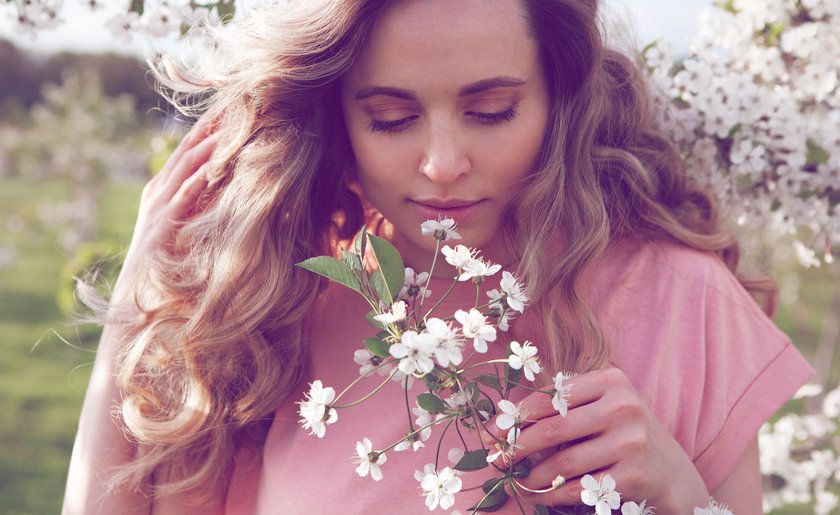 Frau, die an einem Kirschblüte riecht