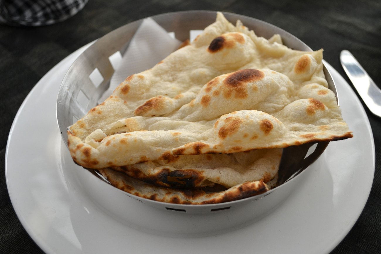 Traditionelles Naan-Brot bekommt durch die Hefe und hohe Hitzezufuhr charakteristische Blasen. Traditionelles Naan-Brot bekommt durch die Hefe und hohe Hitzezufuhr charakteristische Blasen.