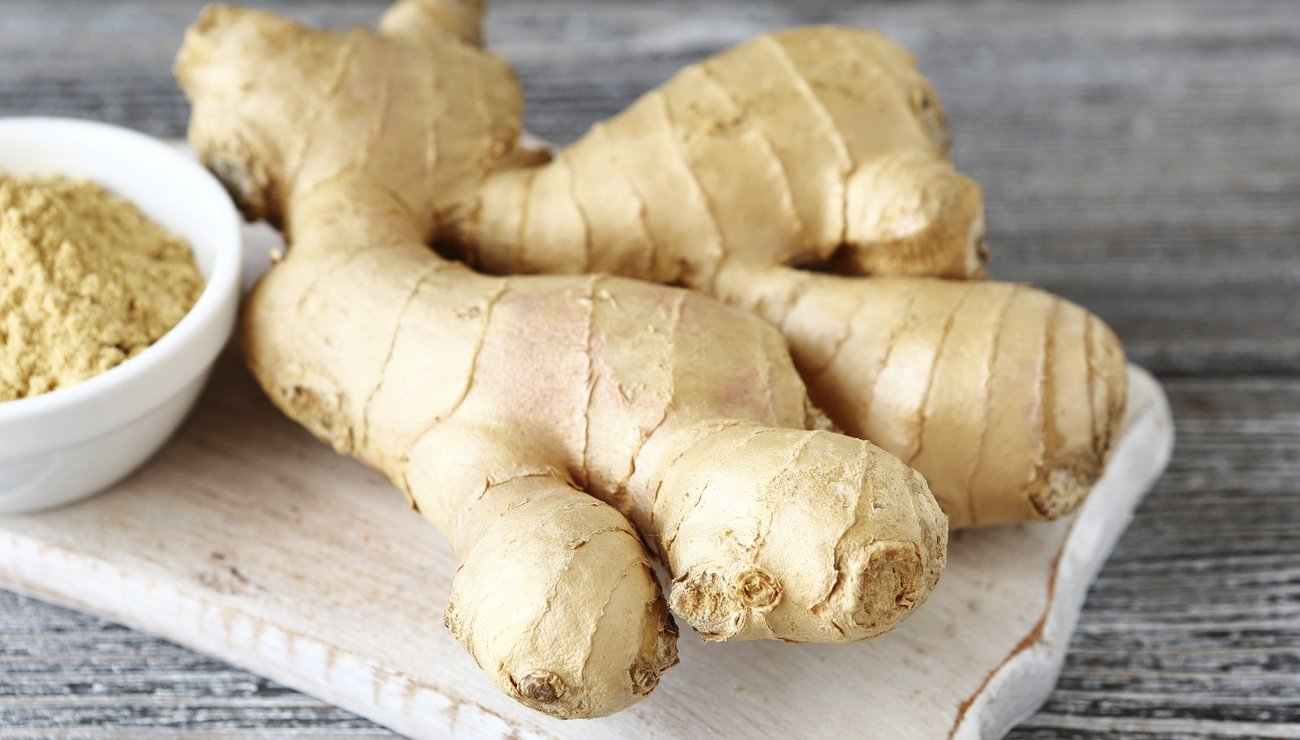 Ginger root on a cutting board with powder, wooden background Ginger root on a cutting board with powder, wooden background