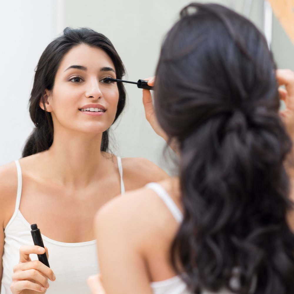 Woman applying black mascara on eyelashes with makeup brush Young beautiful woman applying mascara makeup