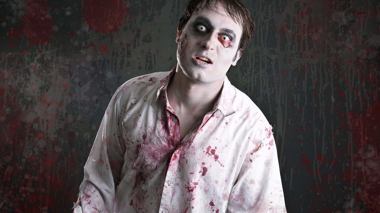 scary zombie with blood splattered white shirt looking into the camera like a zombie does.