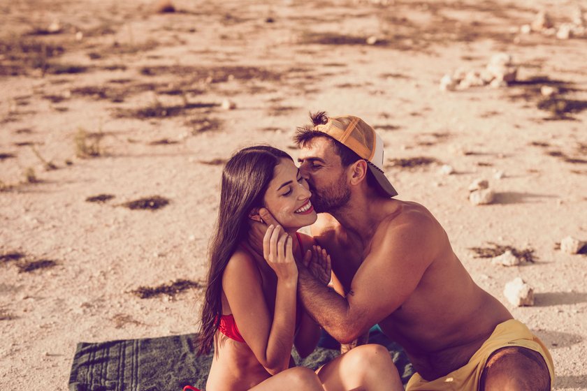 Paar am Strand, Mann küsst Frau auf die Wange