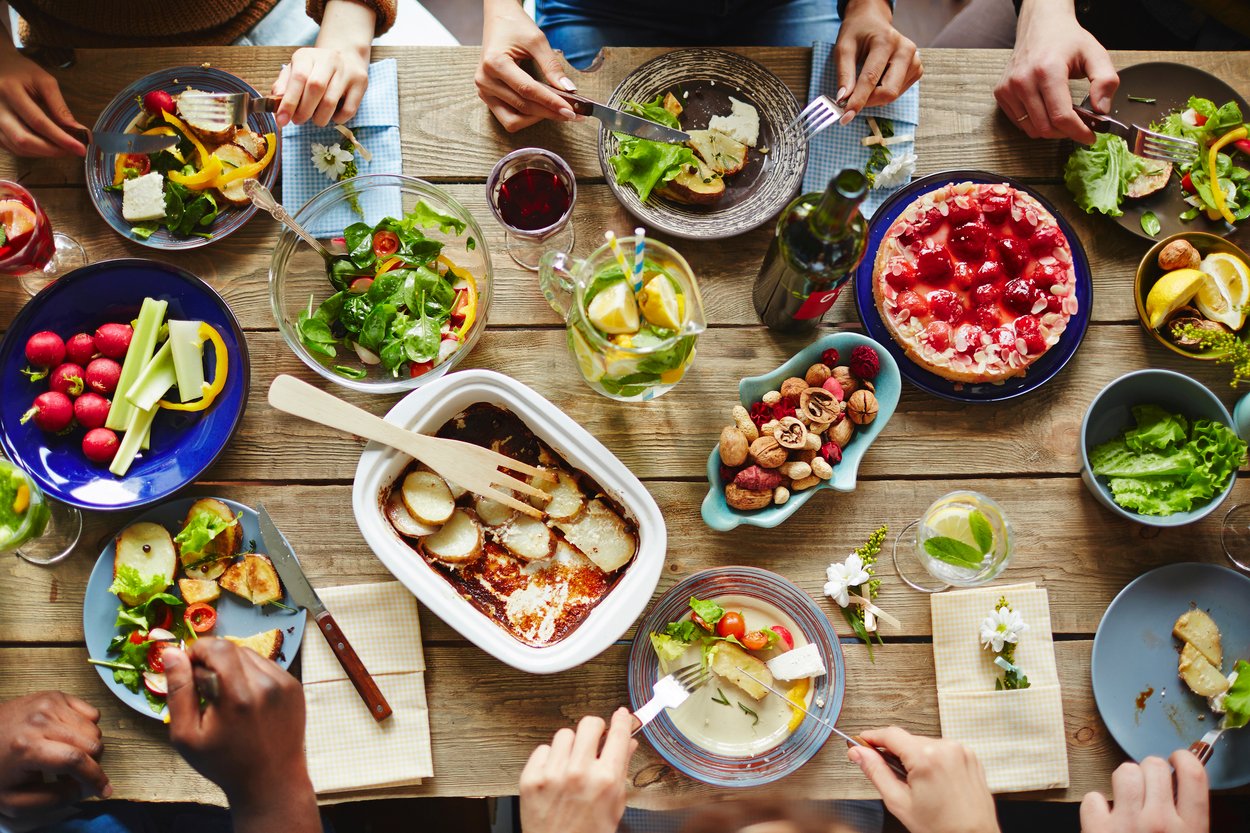 People having a rich dinner with fresh vegetables and homemade meal People having a rich dinner with fresh vegetables and homemade meal