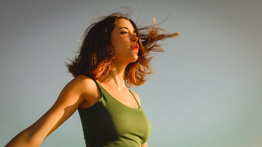 Einer glücklichen Frau weht der Wind durchs Haar