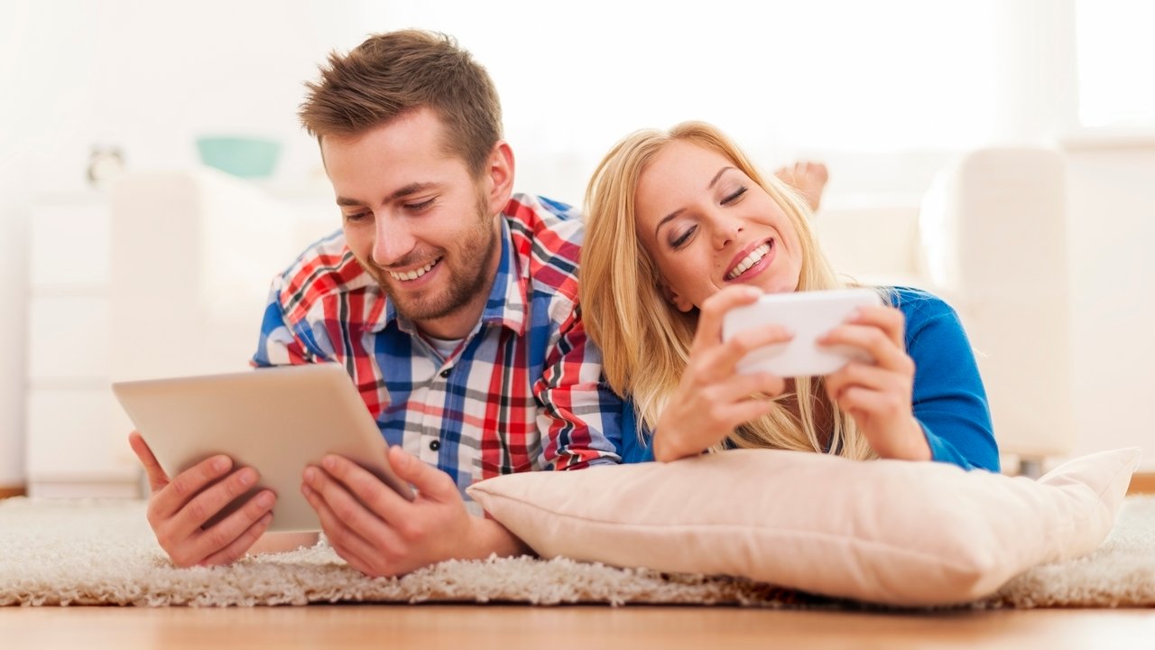 Happy couple spending time with electronic equipment at home