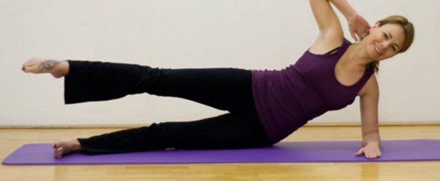 Schritt 1 der Pilatesübung Side Kick Circle, bei der die Pilateslehrerin auf der Seite liegtliegt