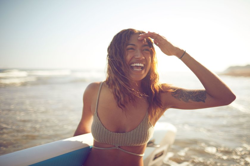 Frau am Strand mit Surfboard in der Hand