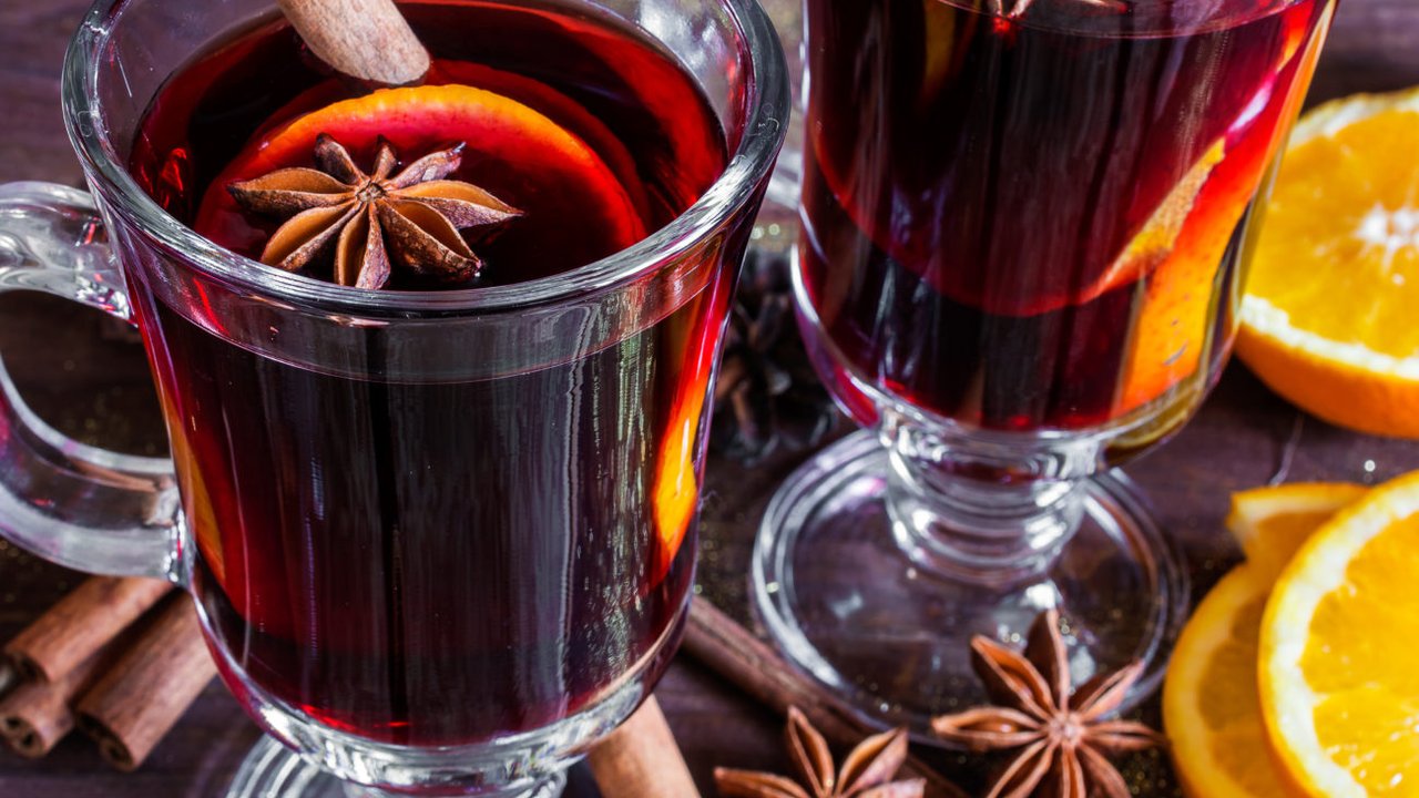 two glasses of hot mulled wine with spices and sliced orange on wooden background. close up