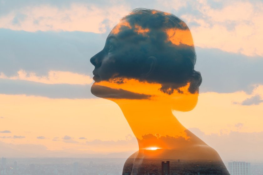 Double exposure of woman face and sunset glow.