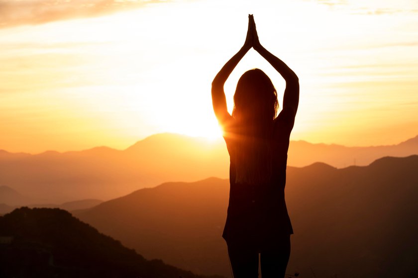 Frau praktiziert Yoga bei Sonnenaufgang