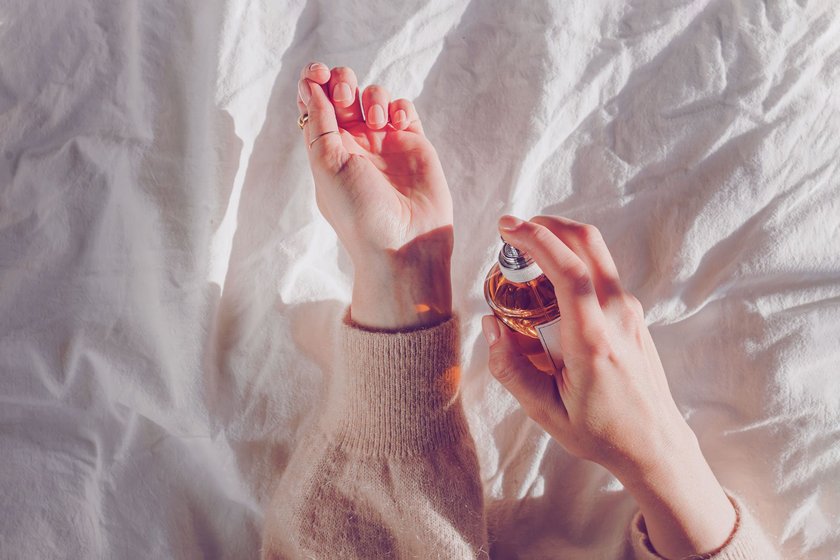 Frau sprüht Parfum auf Handgelenk
