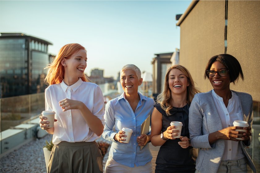 Vier Frauen lachen miteinander und trinken Kaffee
