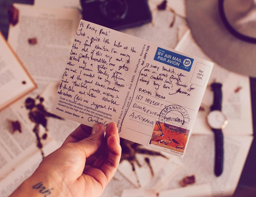 Frau hält beschriebene Postkarte in der Hand