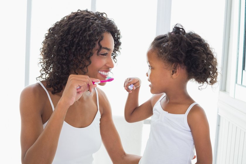 Mutter und Kind putzen gemeinsam Zähne