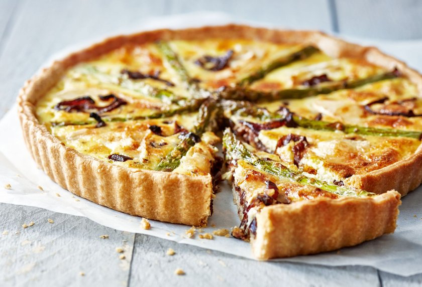 Asparagus quiche on white wooden surface