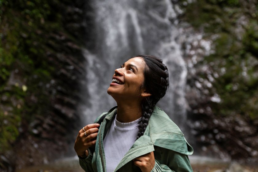 Glückliche Frau steht vor einem Wasserfall