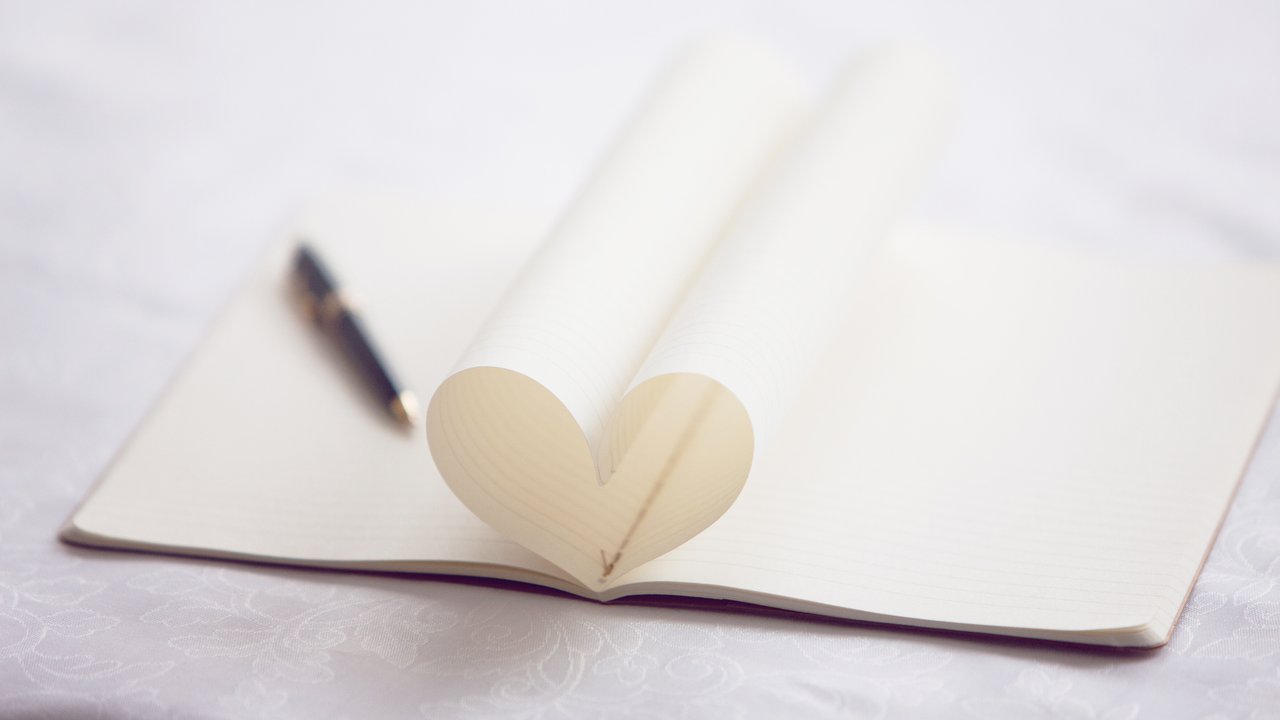 Pen and pages of notebook forming heart-shape