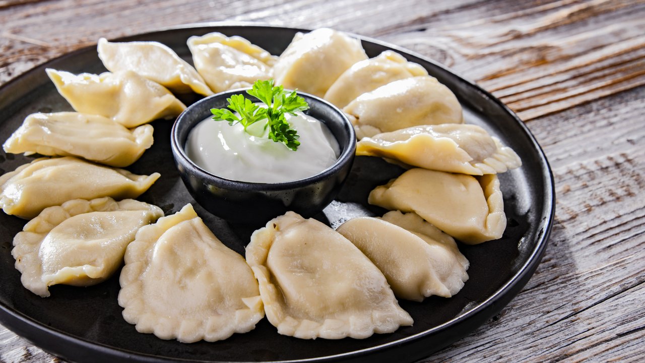 Composition with a plate of classic pierogies with sour cream. Composition with a plate of classic pierogies with sour c