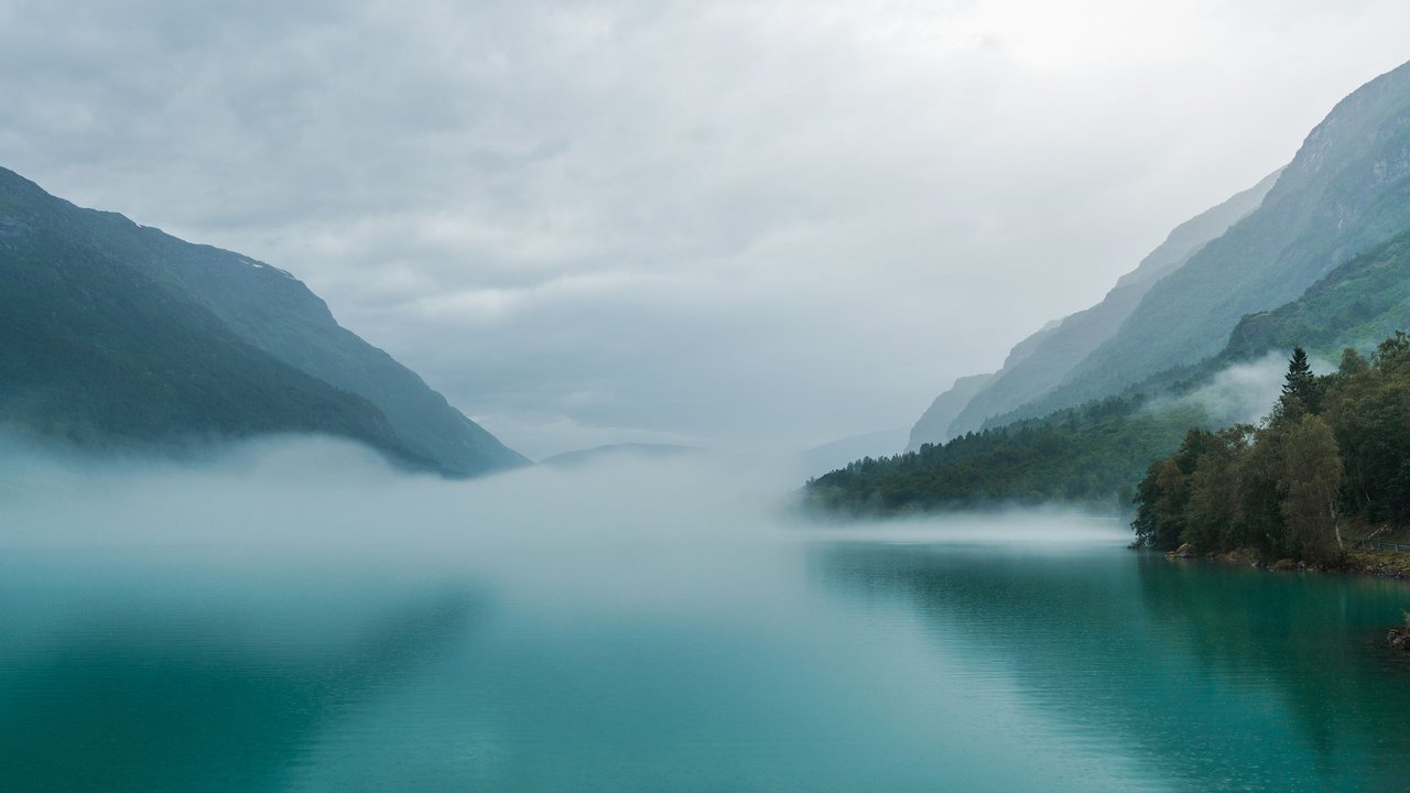 Ein ruhiger See in Norwegen, der mit Nebel bedeckt ist zwischen Bergen